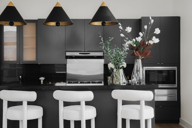 kitchen with decorative backsplash, built in microwave, a kitchen bar, and stainless steel refrigerator