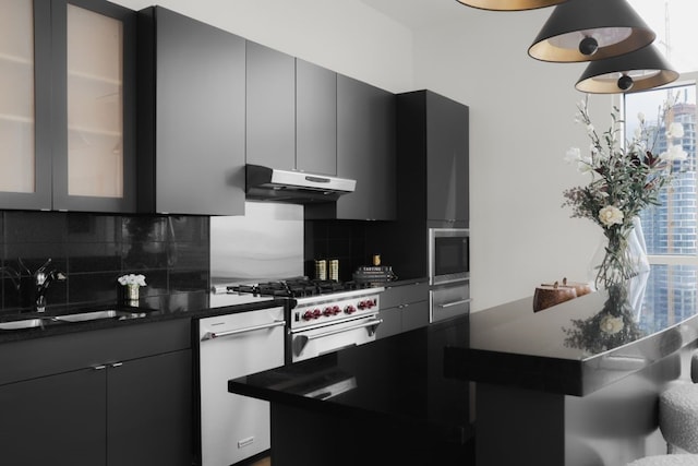 kitchen with appliances with stainless steel finishes, backsplash, dark stone countertops, and sink