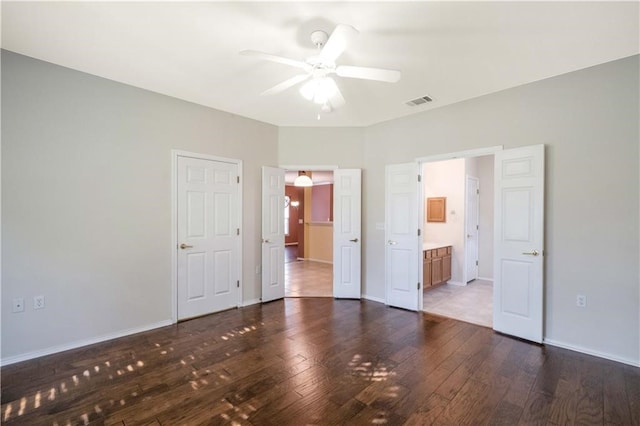 unfurnished bedroom with ceiling fan, ensuite bath, and dark hardwood / wood-style floors