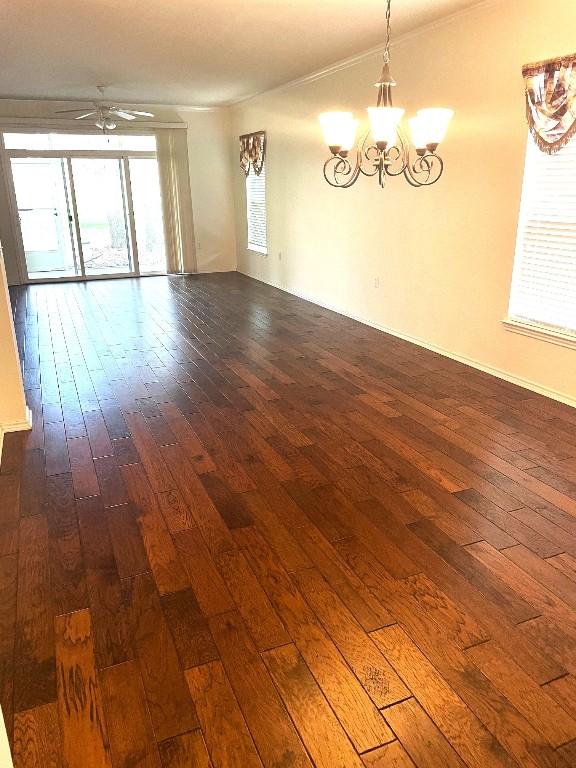 empty room featuring dark hardwood / wood-style flooring and ceiling fan with notable chandelier