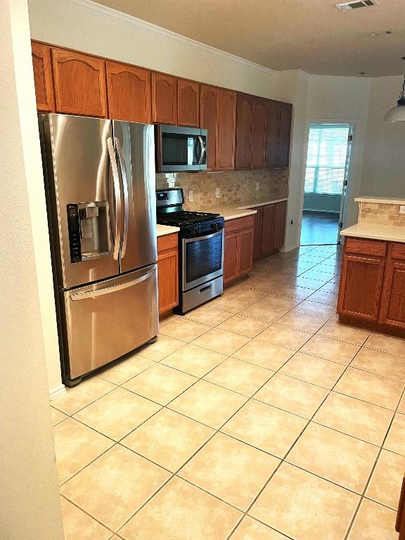 kitchen with stainless steel appliances, crown molding, light tile patterned floors, and backsplash