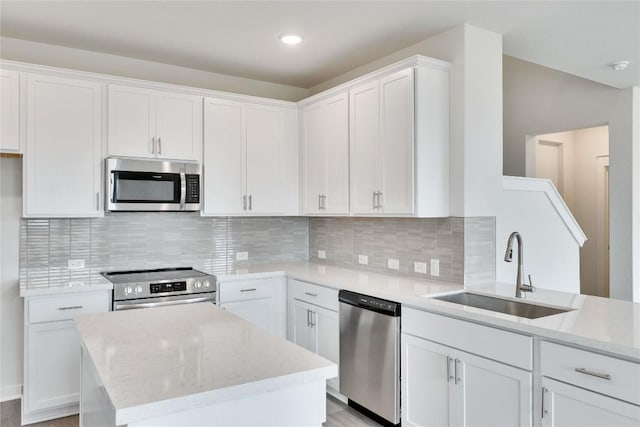 kitchen with a sink, stainless steel appliances, tasteful backsplash, and white cabinets