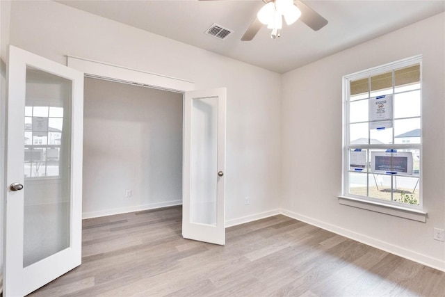 empty room featuring wood finished floors, french doors, visible vents, and baseboards