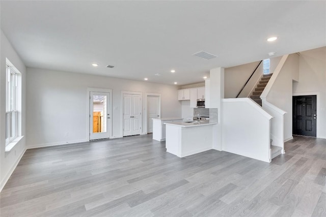 unfurnished living room featuring visible vents, recessed lighting, stairs, and light wood-style floors