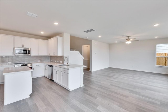 kitchen featuring visible vents, a sink, open floor plan, appliances with stainless steel finishes, and a peninsula