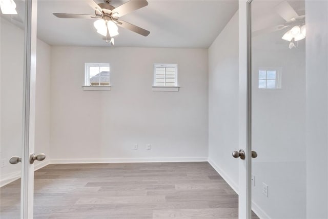 empty room with french doors, baseboards, ceiling fan, and wood finished floors