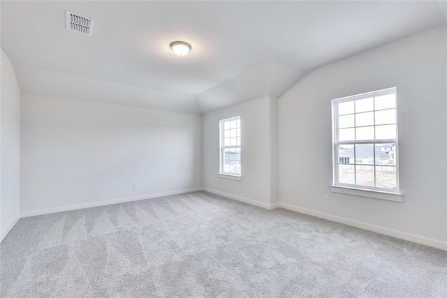 carpeted empty room featuring visible vents, baseboards, and lofted ceiling