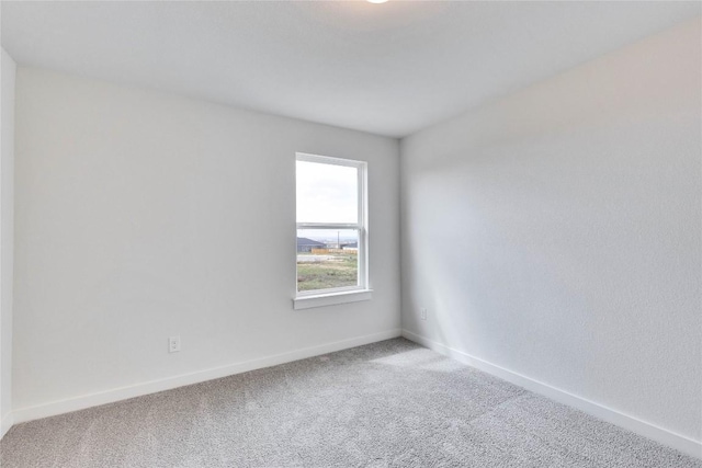 carpeted spare room featuring baseboards