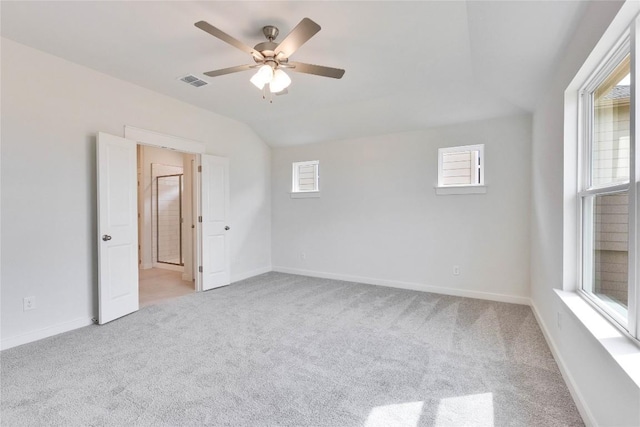 carpeted spare room featuring visible vents, ceiling fan, baseboards, and vaulted ceiling