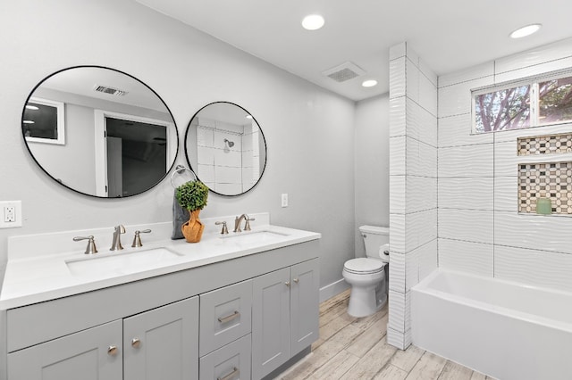 full bathroom with shower / bathing tub combination, hardwood / wood-style flooring, vanity, and toilet