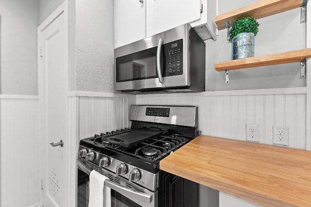 1708 Payne Ave, Austin, TX 78757 - kitchen with appliances with stainless steel finishes, wooden counters, a wainscoted wall, open shelves, and white cabinetry
