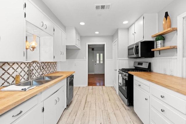 1708 Payne Ave, Austin, TX 78757 - kitchen with stainless steel appliances, a sink, open shelves, white cabinetry, and a wainscoted wall