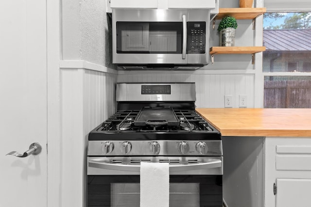 kitchen with white cabinets, appliances with stainless steel finishes, and butcher block countertops