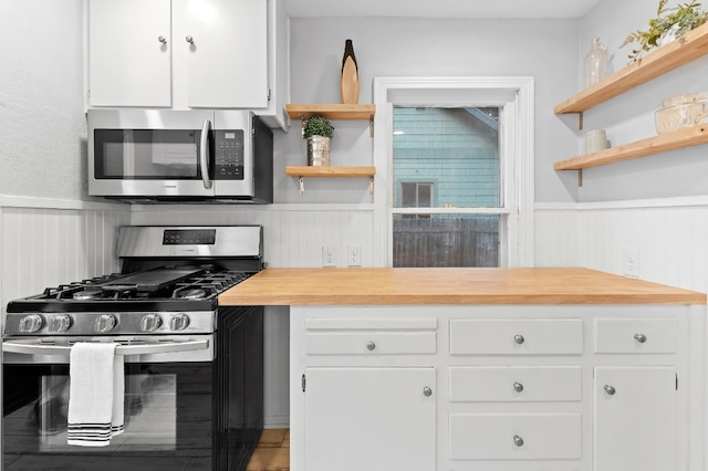 kitchen with white cabinets, stainless steel appliances, and wood counters