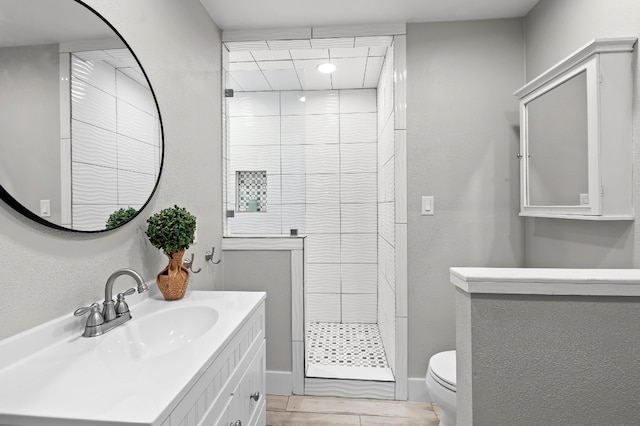 bathroom featuring tiled shower, vanity, and toilet