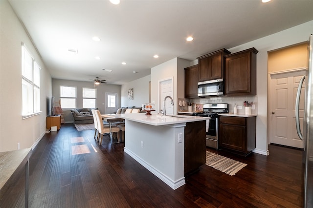 kitchen featuring an island with sink, dark wood-type flooring, sink, and stainless steel appliances