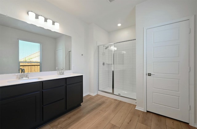 bathroom with a shower with door, hardwood / wood-style floors, and vanity