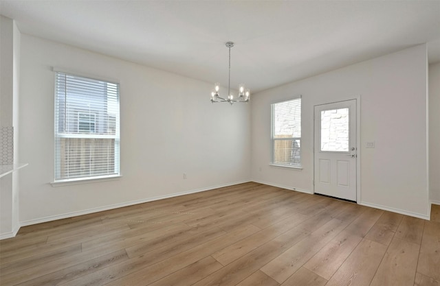 spare room with a chandelier and light hardwood / wood-style floors