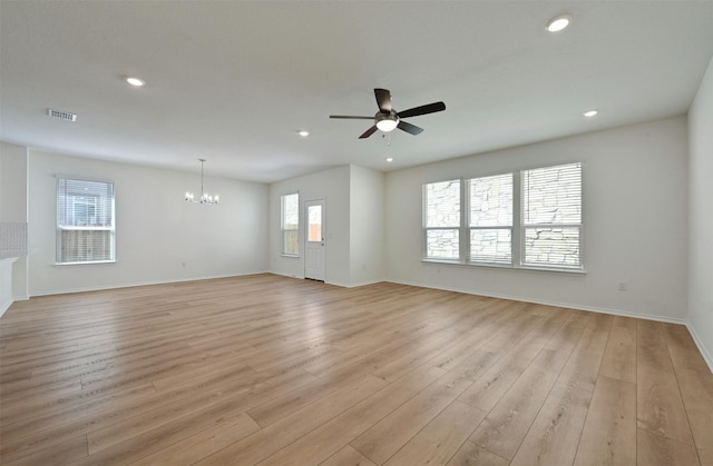 unfurnished living room with ceiling fan with notable chandelier and light hardwood / wood-style flooring