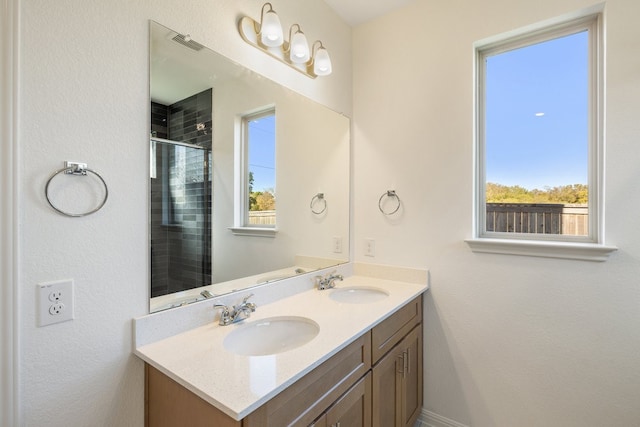 bathroom featuring vanity, a wealth of natural light, and a shower with shower door