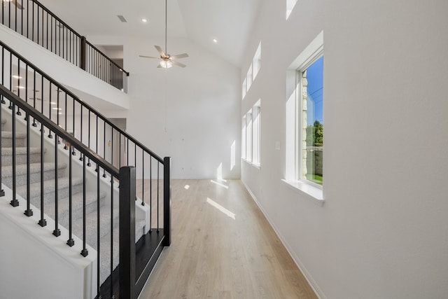 stairway featuring ceiling fan, high vaulted ceiling, and wood-type flooring