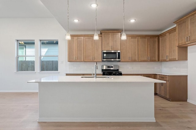 kitchen featuring a center island with sink, pendant lighting, sink, and appliances with stainless steel finishes