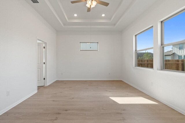 spare room featuring a tray ceiling, ceiling fan, and light hardwood / wood-style flooring