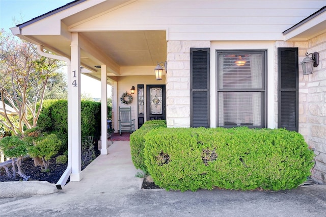 view of exterior entry featuring covered porch and stone siding