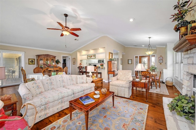 living room featuring wood-type flooring, ceiling fan, crown molding, and a stone fireplace