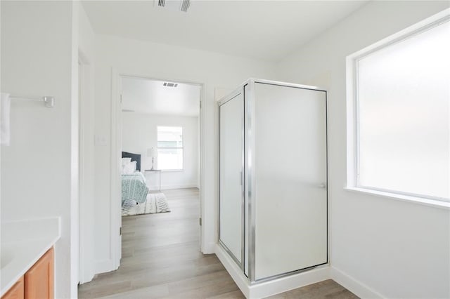 bathroom with wood-type flooring, vanity, and a shower with shower door