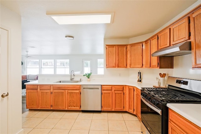 kitchen featuring appliances with stainless steel finishes, light tile patterned floors, ceiling fan, a skylight, and sink