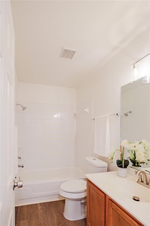 full bathroom with vanity, tiled shower / bath combo, toilet, and hardwood / wood-style flooring