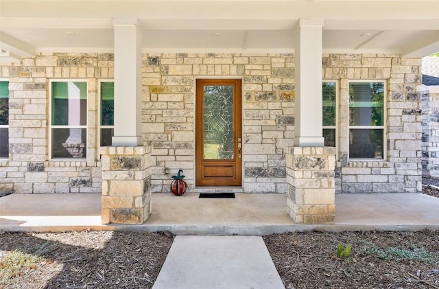 doorway to property with stone siding and a porch