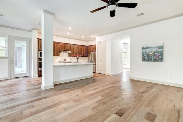 kitchen with appliances with stainless steel finishes, backsplash, ceiling fan, crown molding, and light hardwood / wood-style flooring