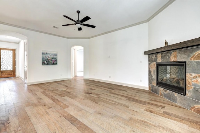 unfurnished living room featuring ceiling fan, crown molding, a fireplace, and light hardwood / wood-style floors