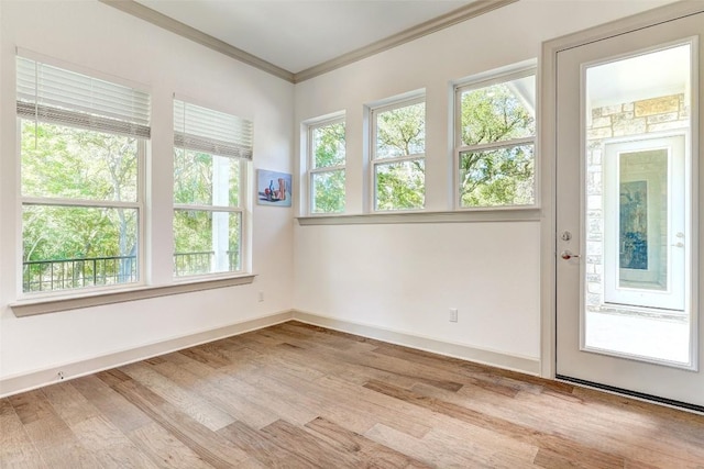 spare room featuring ornamental molding, baseboards, and wood finished floors