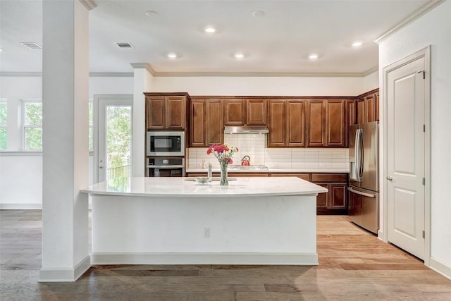 kitchen featuring a kitchen island with sink, ornamental molding, and appliances with stainless steel finishes