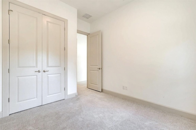 unfurnished bedroom with baseboards, visible vents, a closet, and light colored carpet