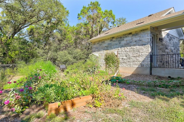 view of home's exterior featuring stone siding and a garden