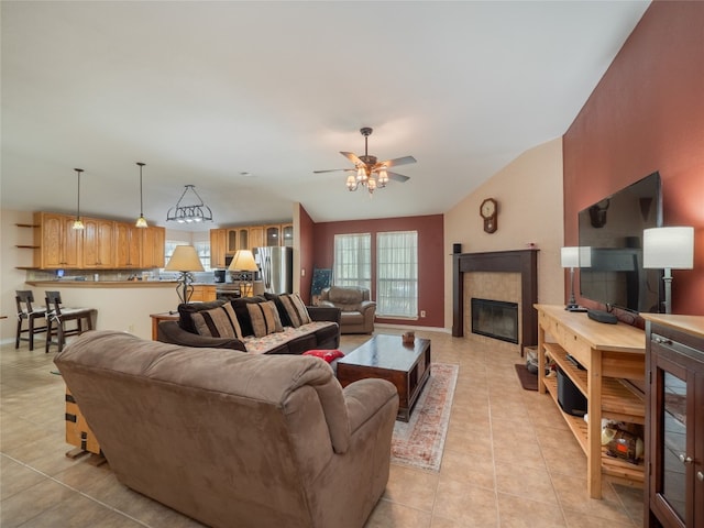 tiled living room with ceiling fan, lofted ceiling, and a tiled fireplace