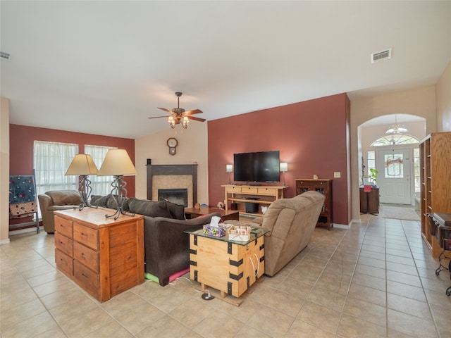 living room featuring a tiled fireplace, ceiling fan, and light tile patterned floors