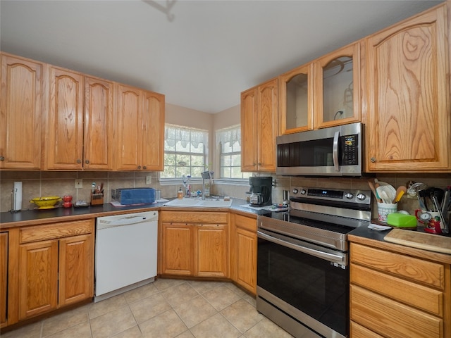 kitchen with light tile patterned flooring, appliances with stainless steel finishes, sink, and tasteful backsplash