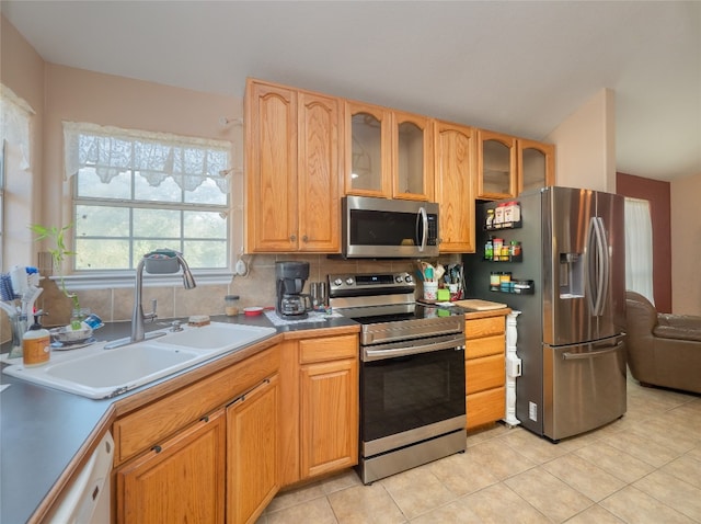 kitchen featuring stainless steel appliances, backsplash, sink, and light tile patterned floors