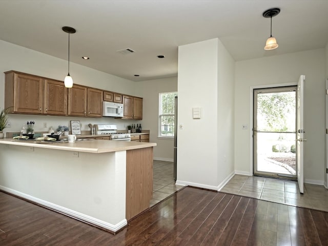 kitchen with kitchen peninsula, white appliances, light hardwood / wood-style floors, and decorative light fixtures