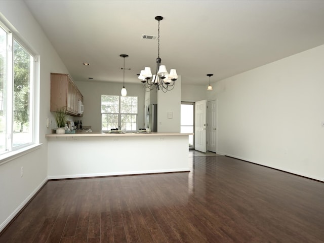 kitchen with stainless steel refrigerator, plenty of natural light, dark wood-type flooring, and kitchen peninsula