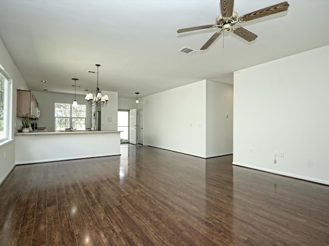 unfurnished living room featuring ceiling fan with notable chandelier and dark wood-type flooring