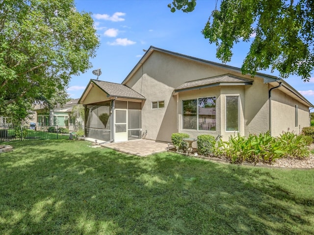 back of house featuring a lawn, a sunroom, and a patio area