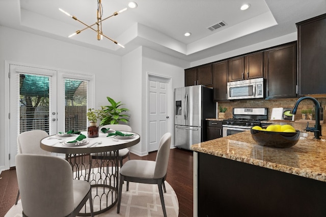 kitchen featuring light stone countertops, stainless steel appliances, a raised ceiling, and dark hardwood / wood-style flooring