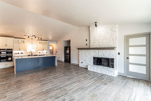 kitchen with hardwood / wood-style flooring, hanging light fixtures, vaulted ceiling, and black appliances