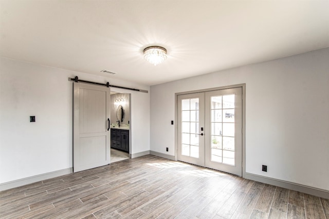 interior space featuring french doors, light hardwood / wood-style flooring, and a barn door